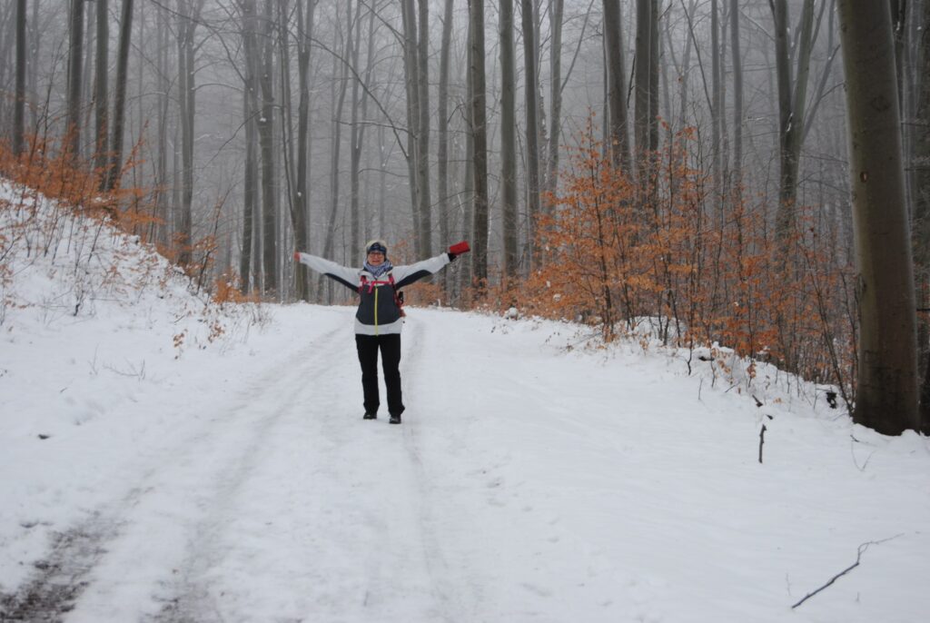 Seniorka spaceruje przez las zimą