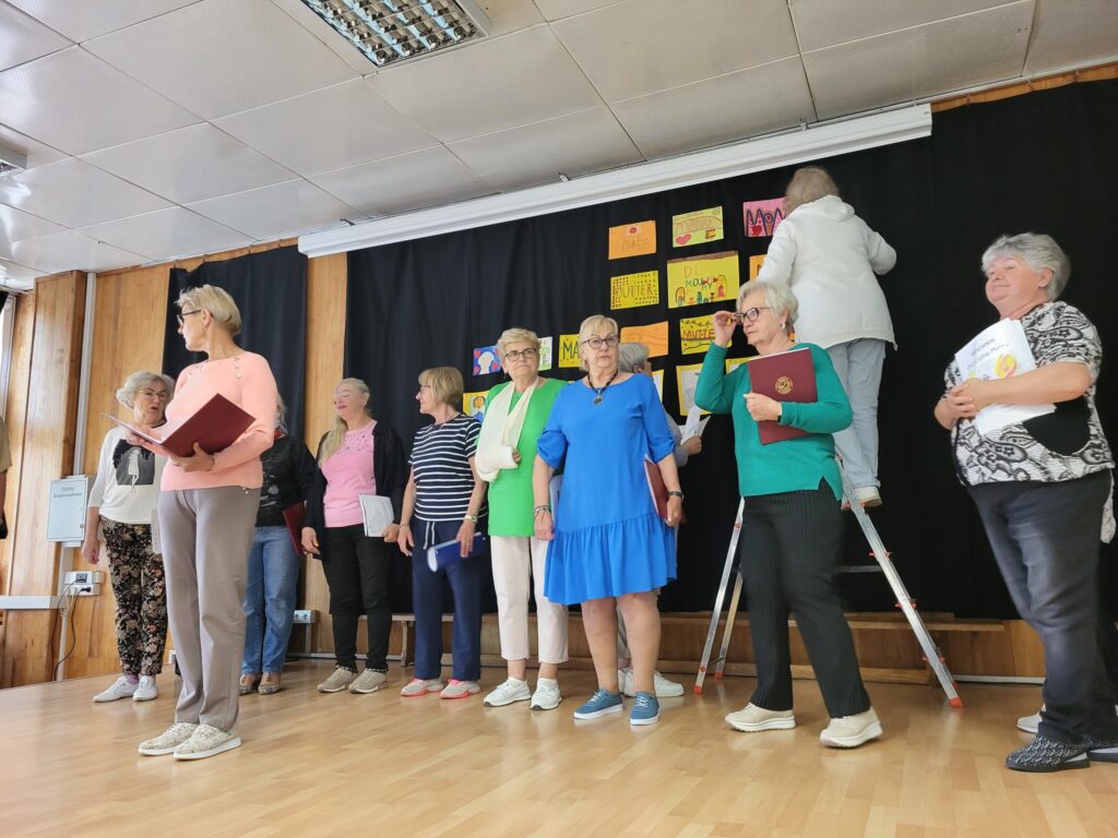 Zdjęcie przedstawia seniorki biorące udział w próbie generalnej przed koncertem z okazji Dnia Matki w klubie "Dąb"