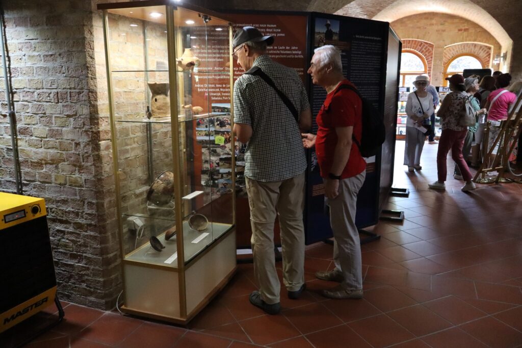 zdjęcie przedstawia uczestników wycieczki zwiedzających z lokalną przewodniczką Muzeum Twierdzy Kostrzyn