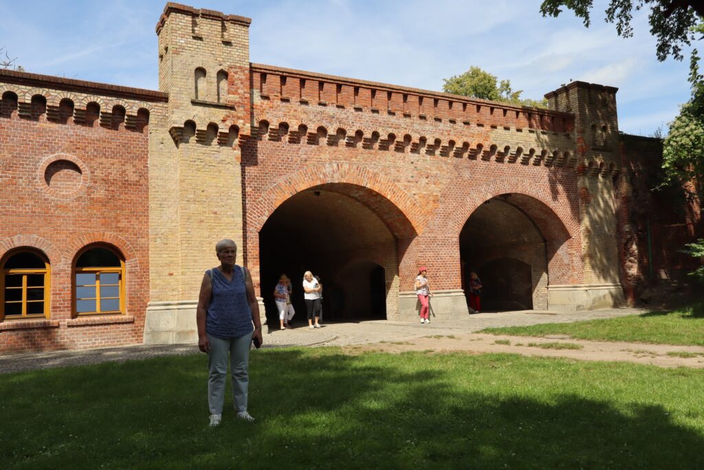 zdjęcie przedstawia uczestników wycieczki zwiedzających z lokalną przewodniczką Muzeum Twierdzy Kostrzyn