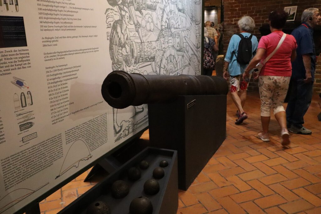 zdjęcie przedstawia uczestników wycieczki zwiedzających z lokalną przewodniczką Muzeum Twierdzy Kostrzyn