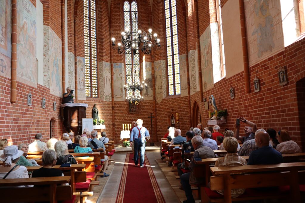 zdjęcie przedstawia uczestników wycieczki zwiedzających z lokalną przewodniczką Muzeum Twierdzy Kostrzyn