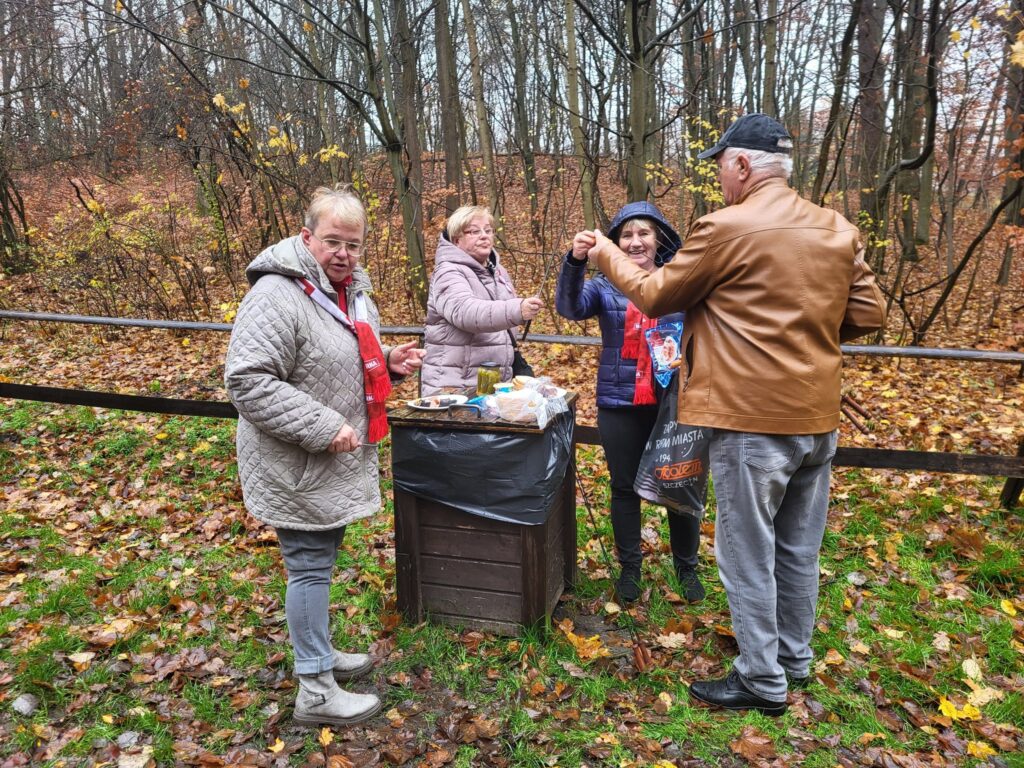 zdjęcie przedstawia uczestników obchodów Święta Niepodległości z Klubu Seniora "Dąb" - mimo niepogody