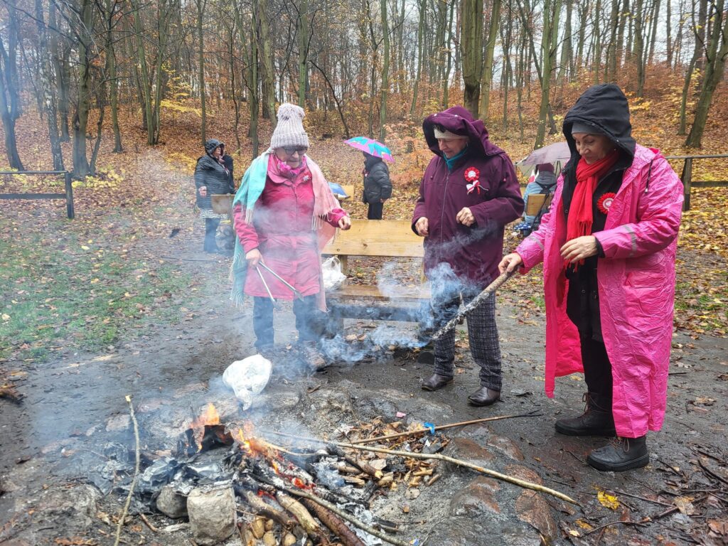 zdjęcie przedstawia uczestników obchodów Święta Niepodległości z Klubu Seniora "Dąb" - mimo niepogody