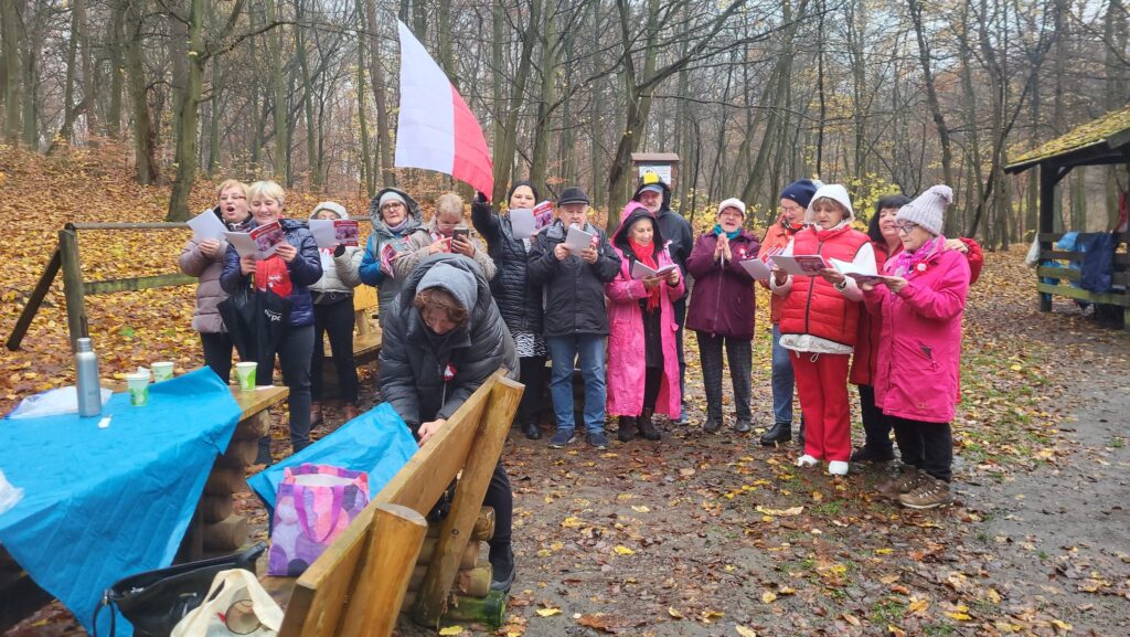 zdjęcie przedstawia uczestników obchodów Święta Niepodległości z Klubu Seniora "Dąb" - mimo niepogody